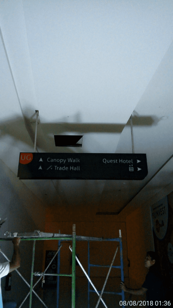 Directional wayfinding sign for Quest Hotel, Trade Hall, and Canopy Walk in Mandaluyong with scaffolding by M&G Global Ads.